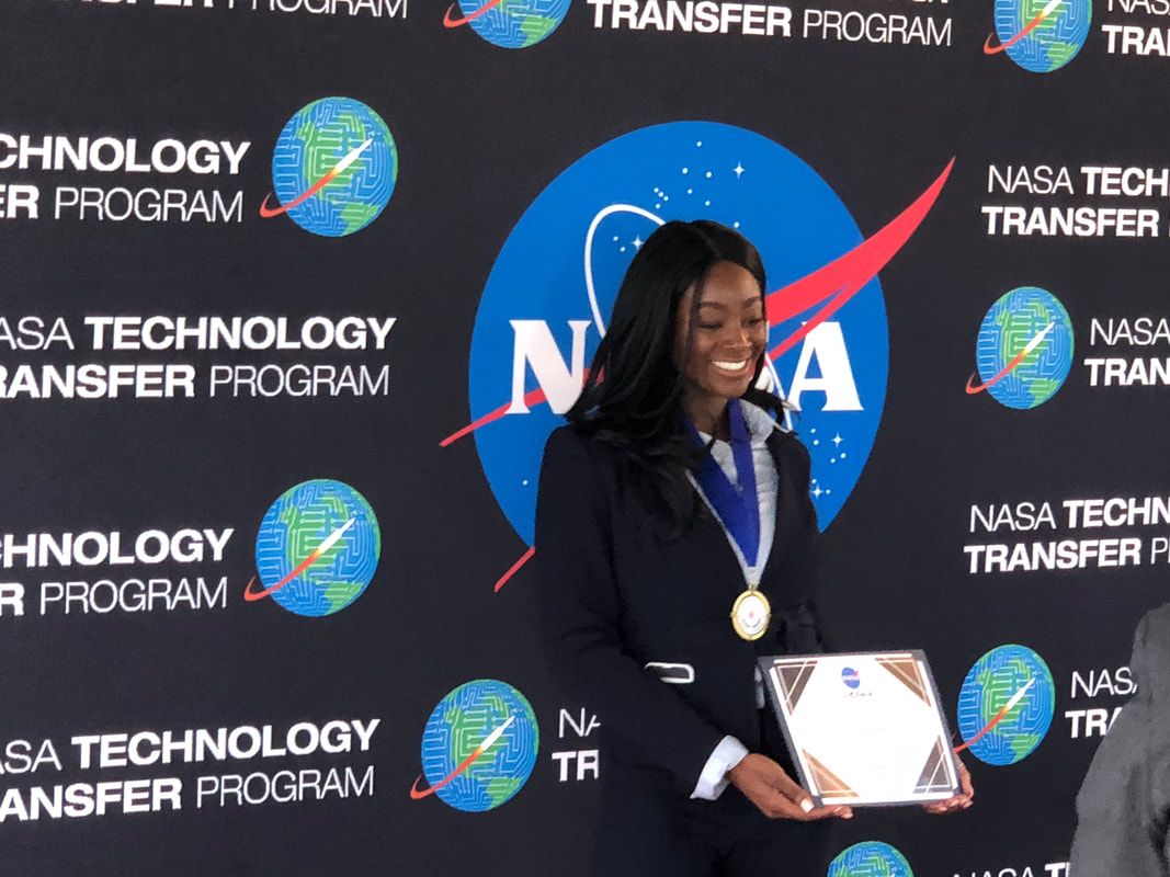 Medal recipient holding an award certificate before the NASA Technology Transfer backdrop