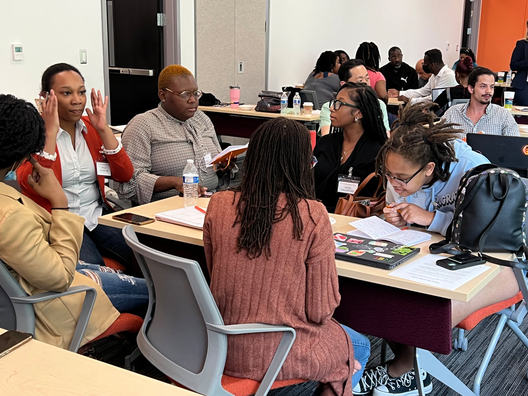 Workshop participants collaborating around tables with laptops and notes