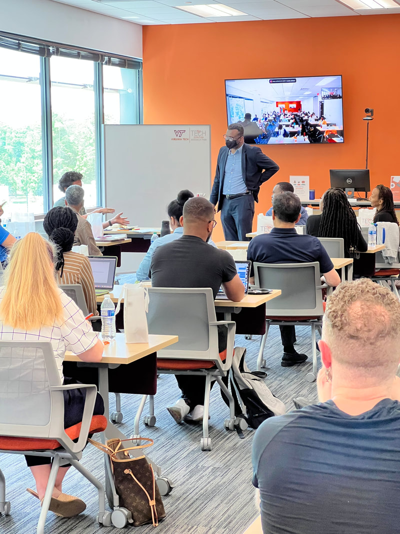 Attendees seated at tables facing a speaker near the workshop presentation screens