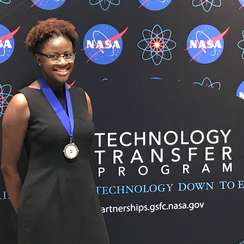 Medal recipient smiling before the NASA Technology Transfer Program backdrop