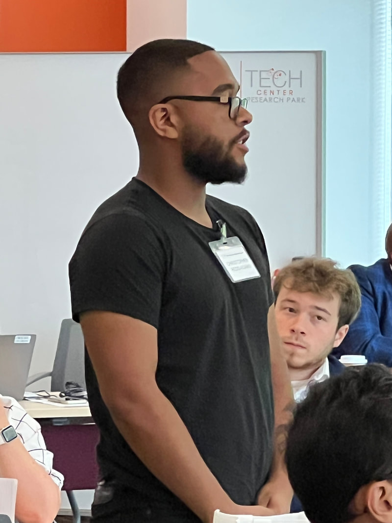 Participant with glasses standing beside a table during workshop introductions