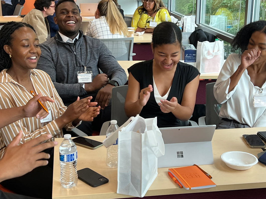 Workshop participants smiling and exchanging ideas around a table