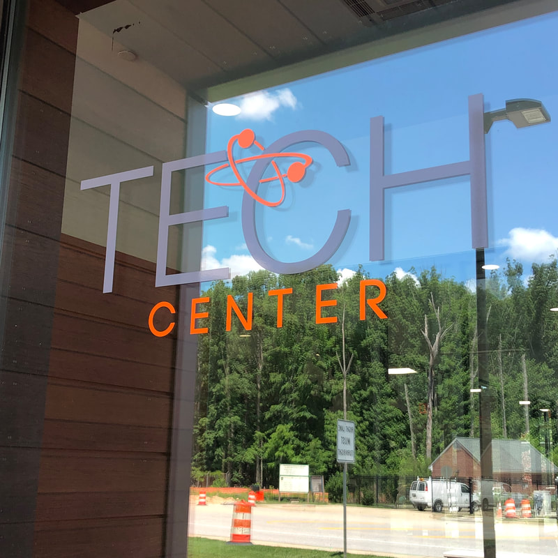Tech Center logo on the glass entrance, with trees reflected outside