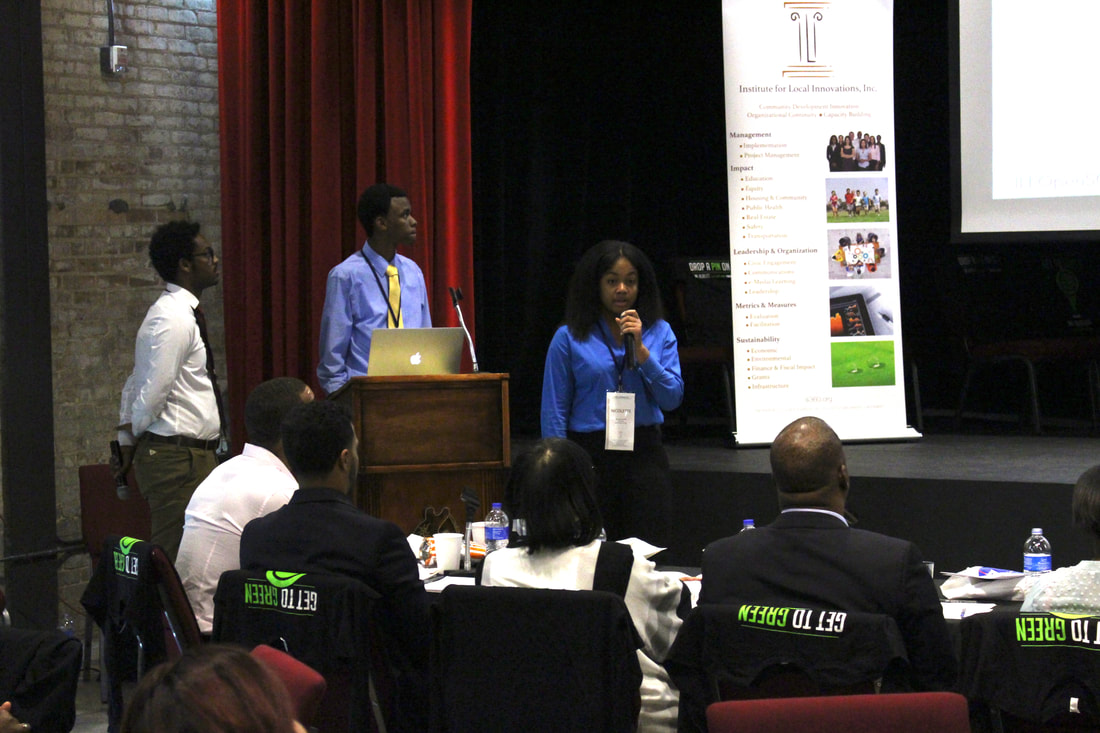 Riverside team members presenting to judges beside the auditorium podium