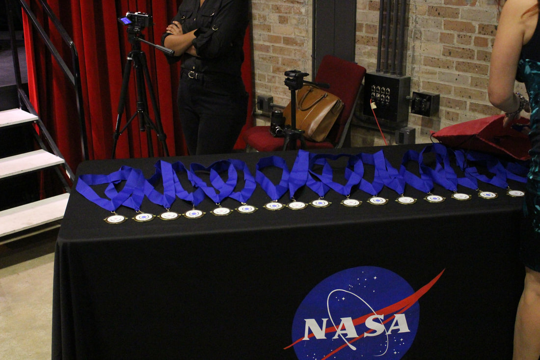 Award medals arranged on a NASA-branded table beside the stage