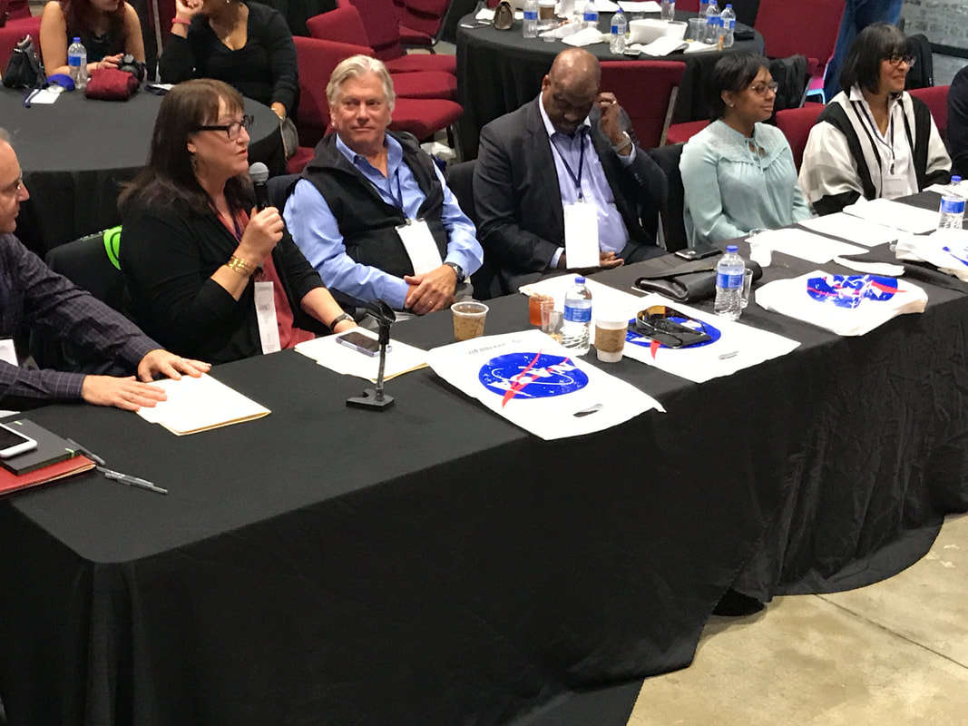 TIME Challenge judges seated at a long table with microphones and presentation materials