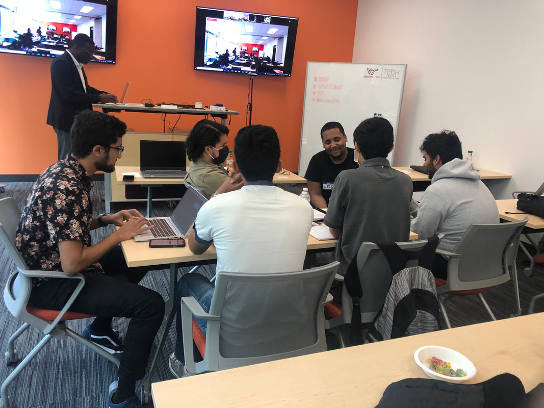Small groups working around tables with laptops and notebooks