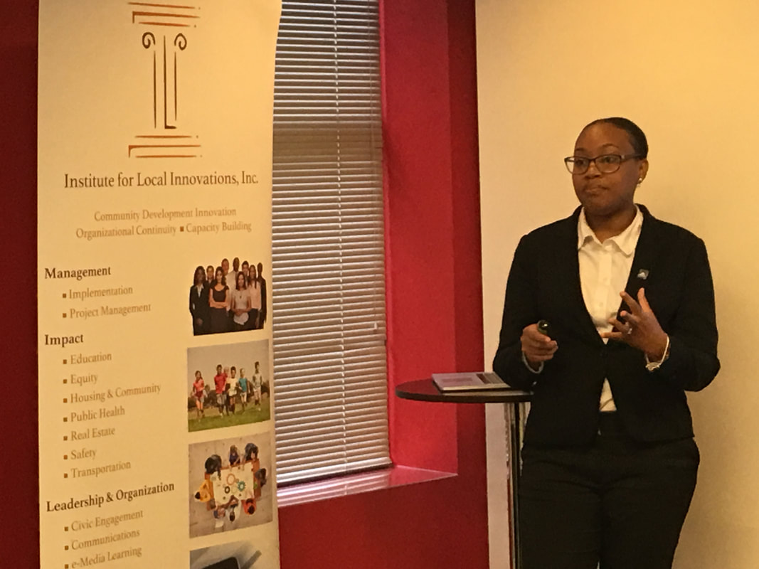 Speaker giving a presentation beside an Institute for Local Innovations banner