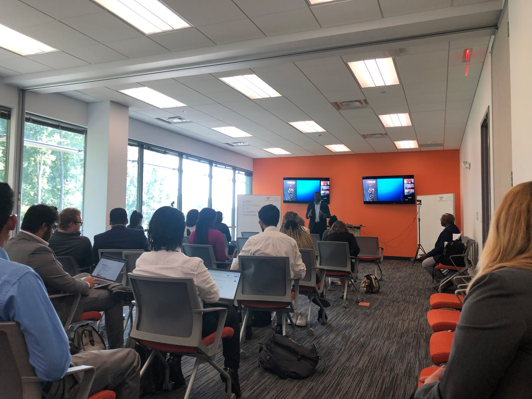 Workshop attendees seated facing a speaker in an orange-walled meeting room