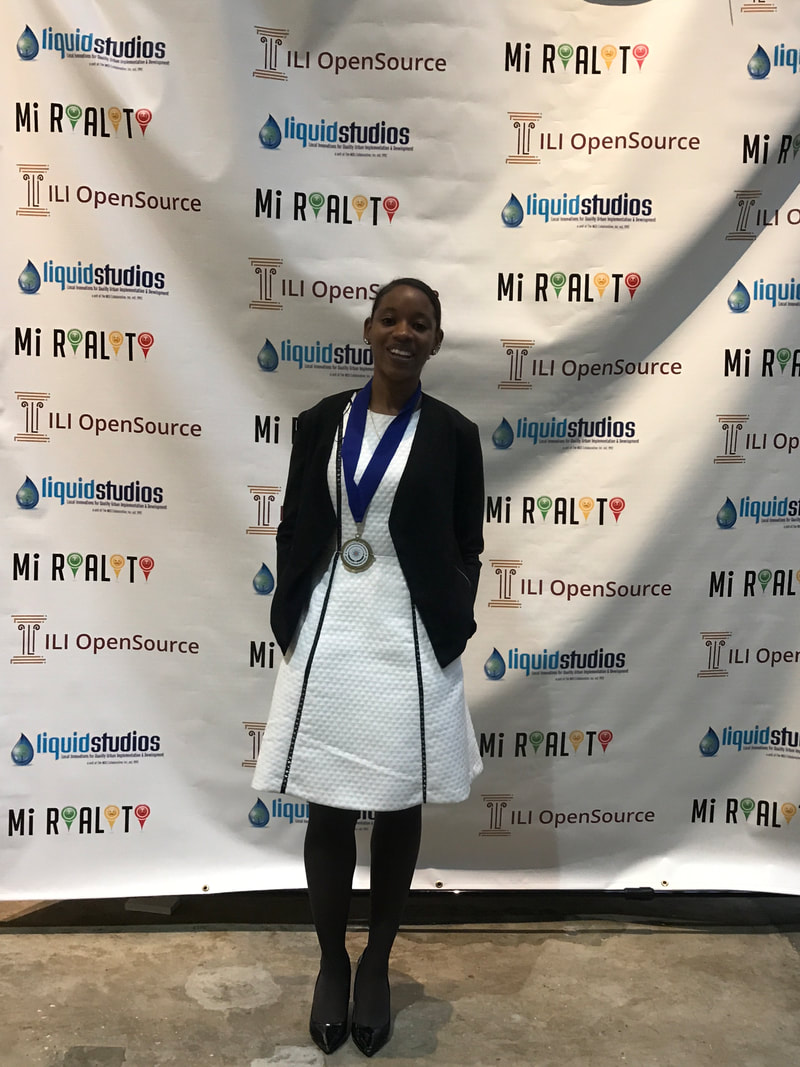 Award recipient posing in a white jacket before the OpenSOURCE event backdrop