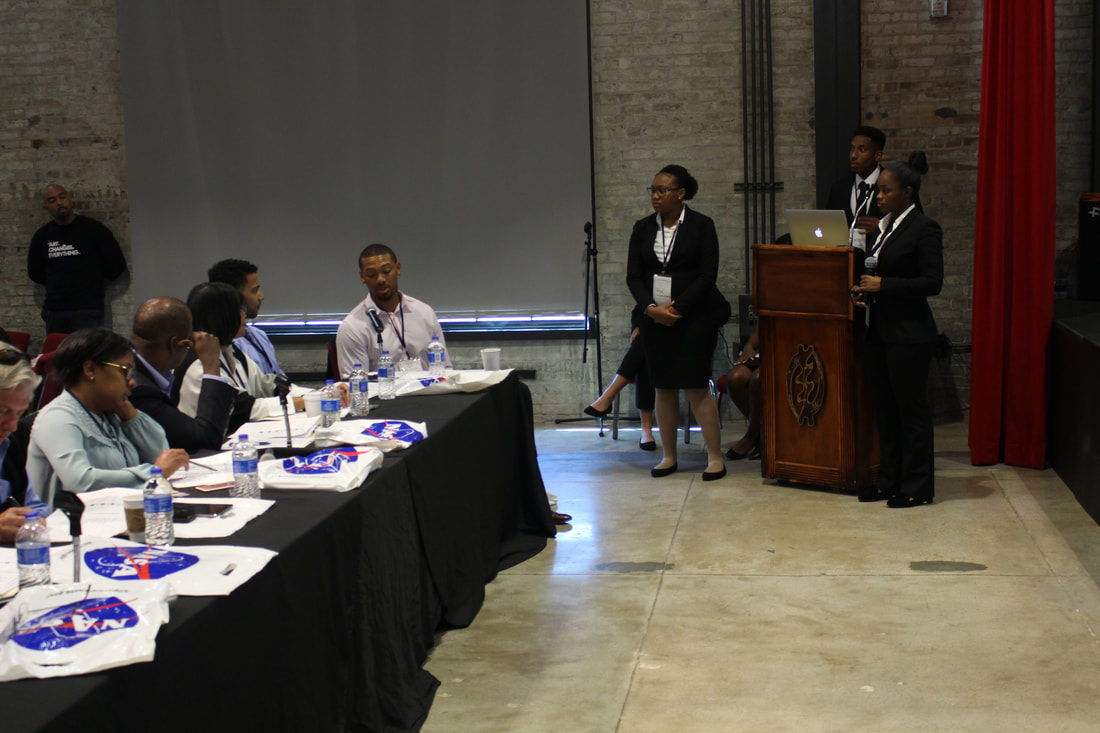 Student presenting at a podium while TIME Challenge judges listen