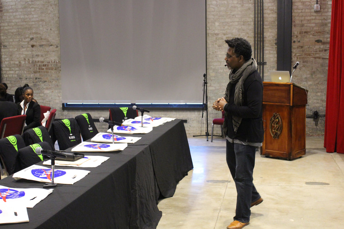 Speaker addressing judges beside a table displaying award medals