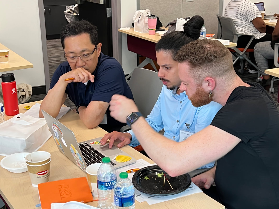 Two participants working side by side with laptops, phones, and notebooks