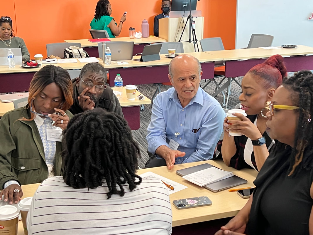 Team members discussing their work around a table with notebooks and a laptop