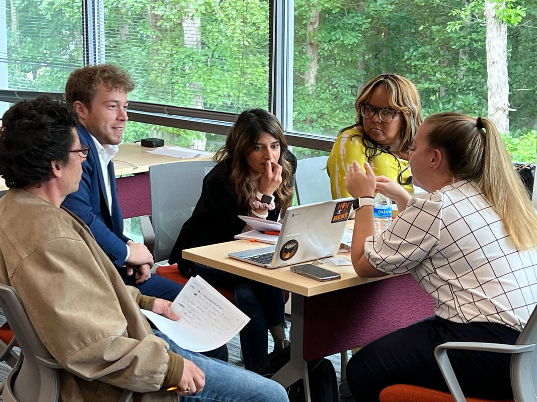 Workshop team comparing notes around a table with an open laptop