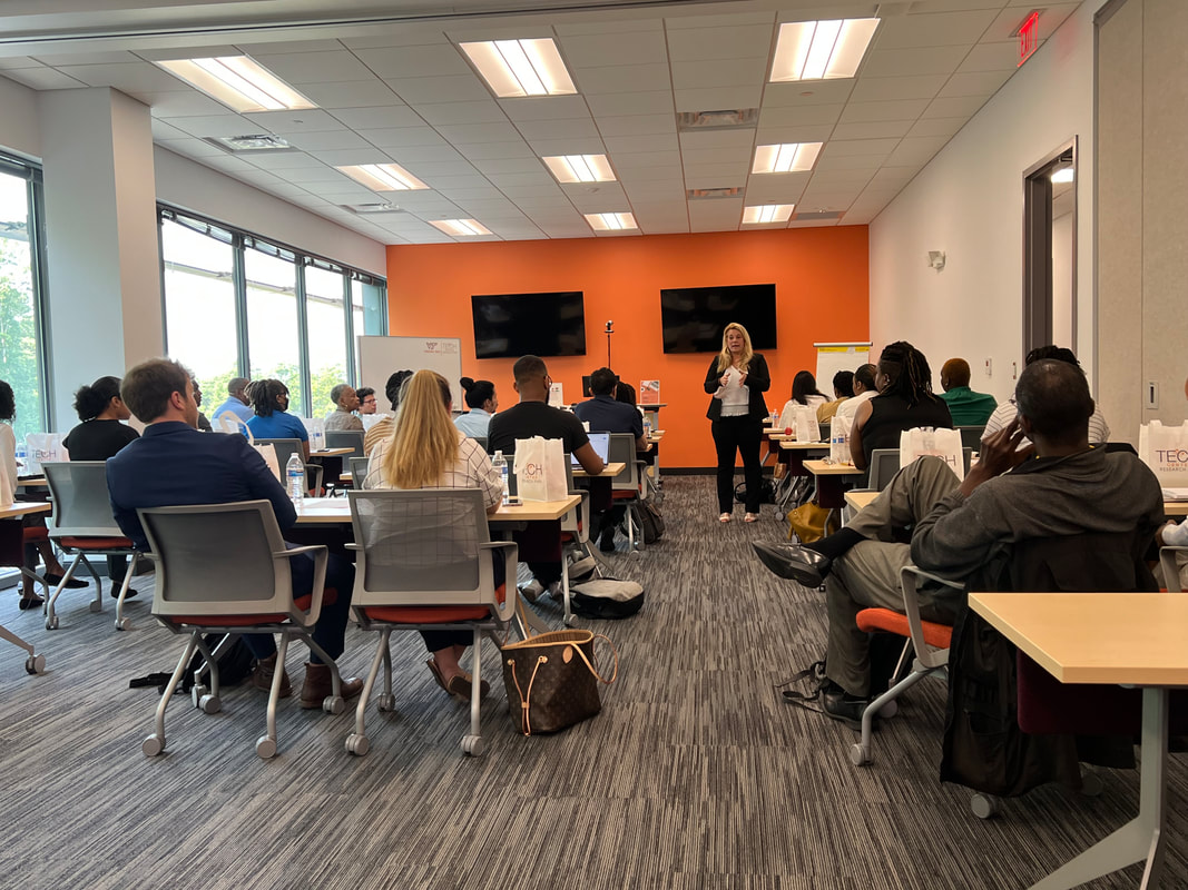 Wide view of the orange-walled workshop room with participants seated around tables