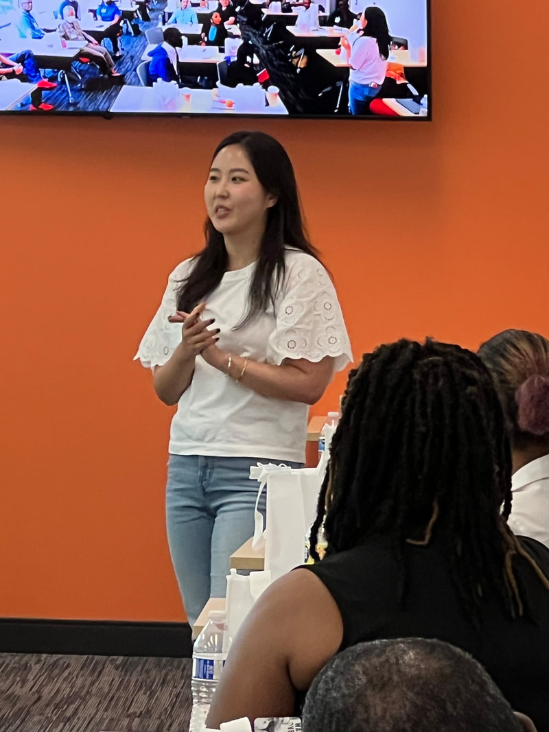 Participant in a patterned blouse gesturing while addressing the workshop group