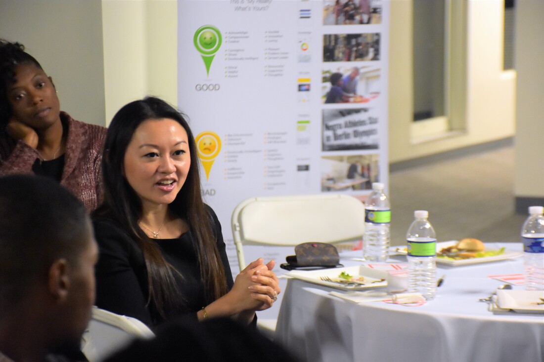 Participant speaking during a round-table discussion with presentation posters behind her